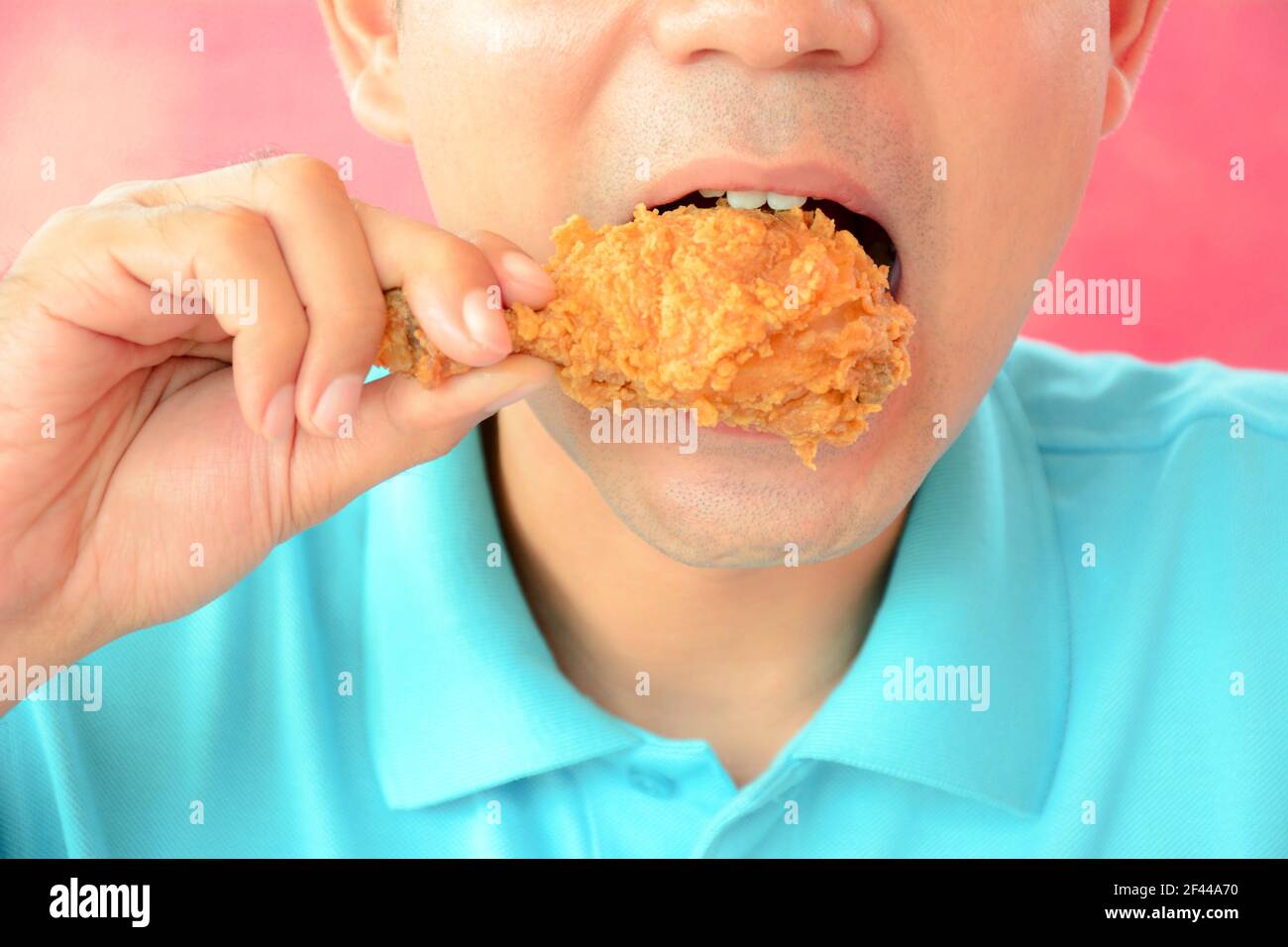 Ein Mann beißt frittiertes Hühnerbein oder Drumstick Stockfoto