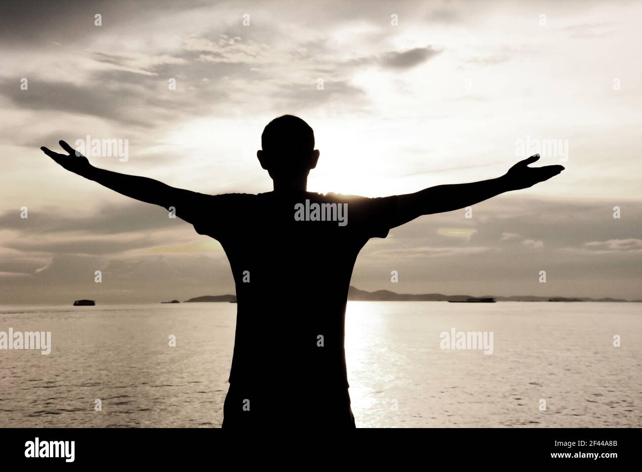 Silhouette eines Mannes, der seine Arme auf See Wasser & Himmel Hintergrund - glücklich, entspannen & Erfolg Konzept Stockfoto