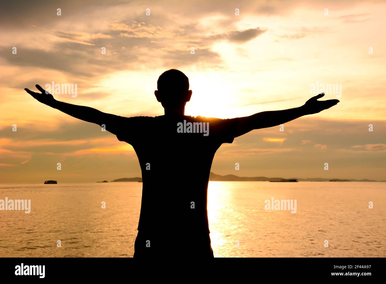 Silhouette eines Mannes, der seine Arme auf Meerwasser und Dämmerung Himmel Hintergrund - glücklich, entspannen & Erfolg Konzept Stockfoto