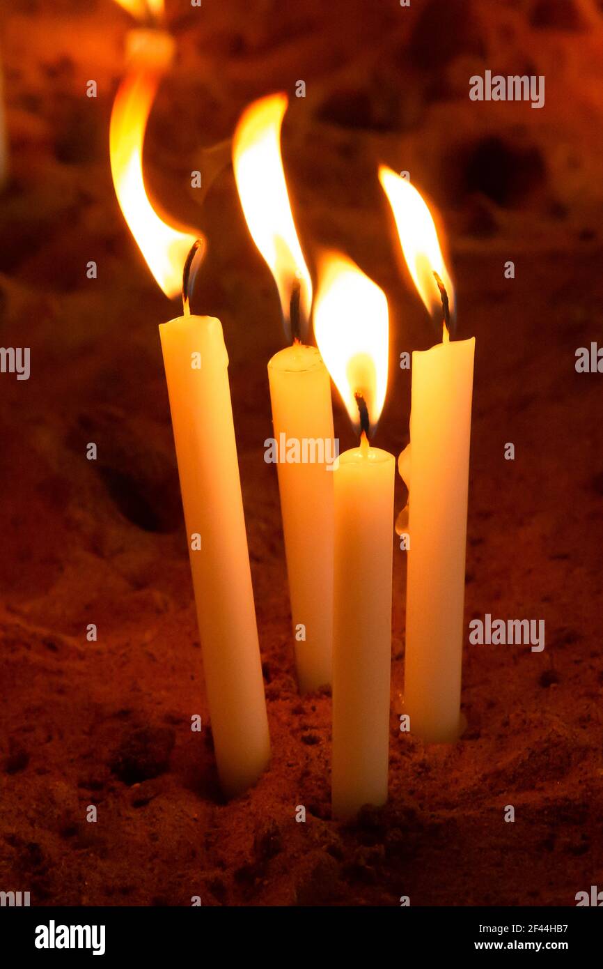 Eine Gruppe von brennenden oder brennenden Gebetskerzen in einem Sandkasten Stockfoto
