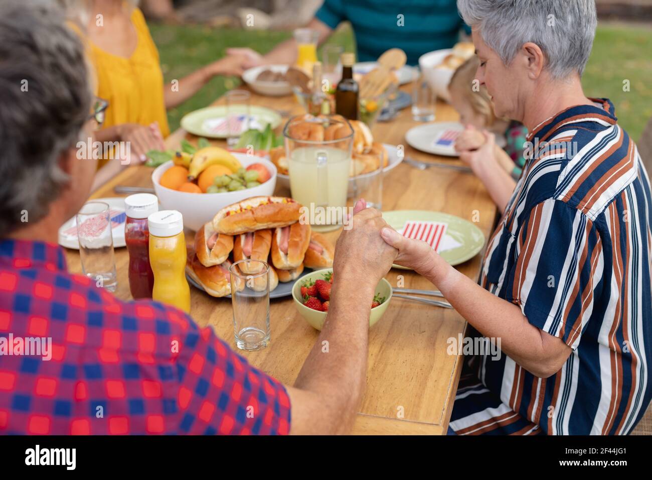 Kaukasische drei-Generationen-Familie hält Hände sagen Gnade vor dem Essen Gemeinsames Essen im Garten Stockfoto