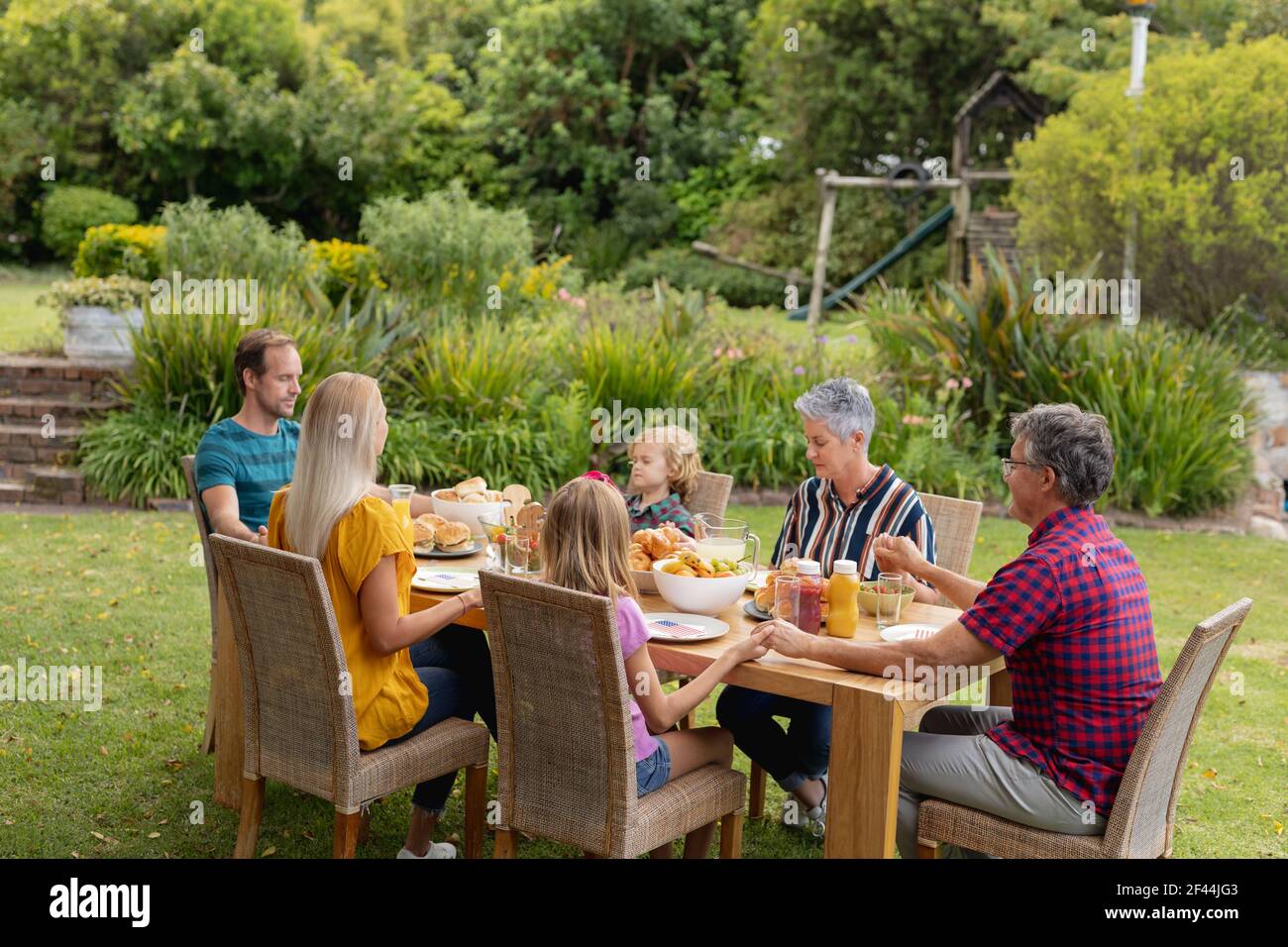 Kaukasische drei-Generationen-Familie hält Hände sagen Gnade vor dem Essen Gemeinsames Essen im Garten Stockfoto