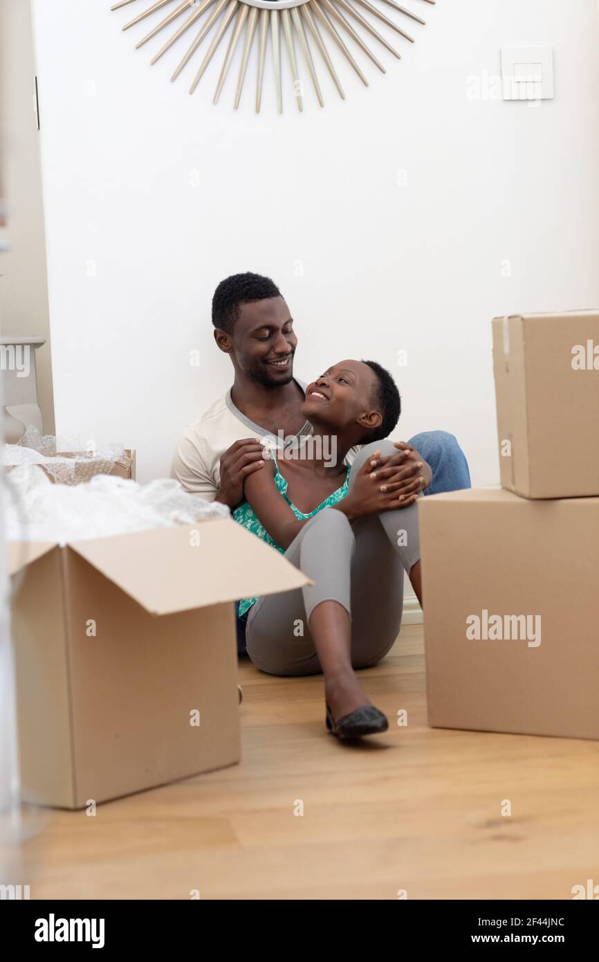 afroamerikanisches Paar Umzug Haus Auspacken sitzen auf dem Boden und Umarmen Stockfoto