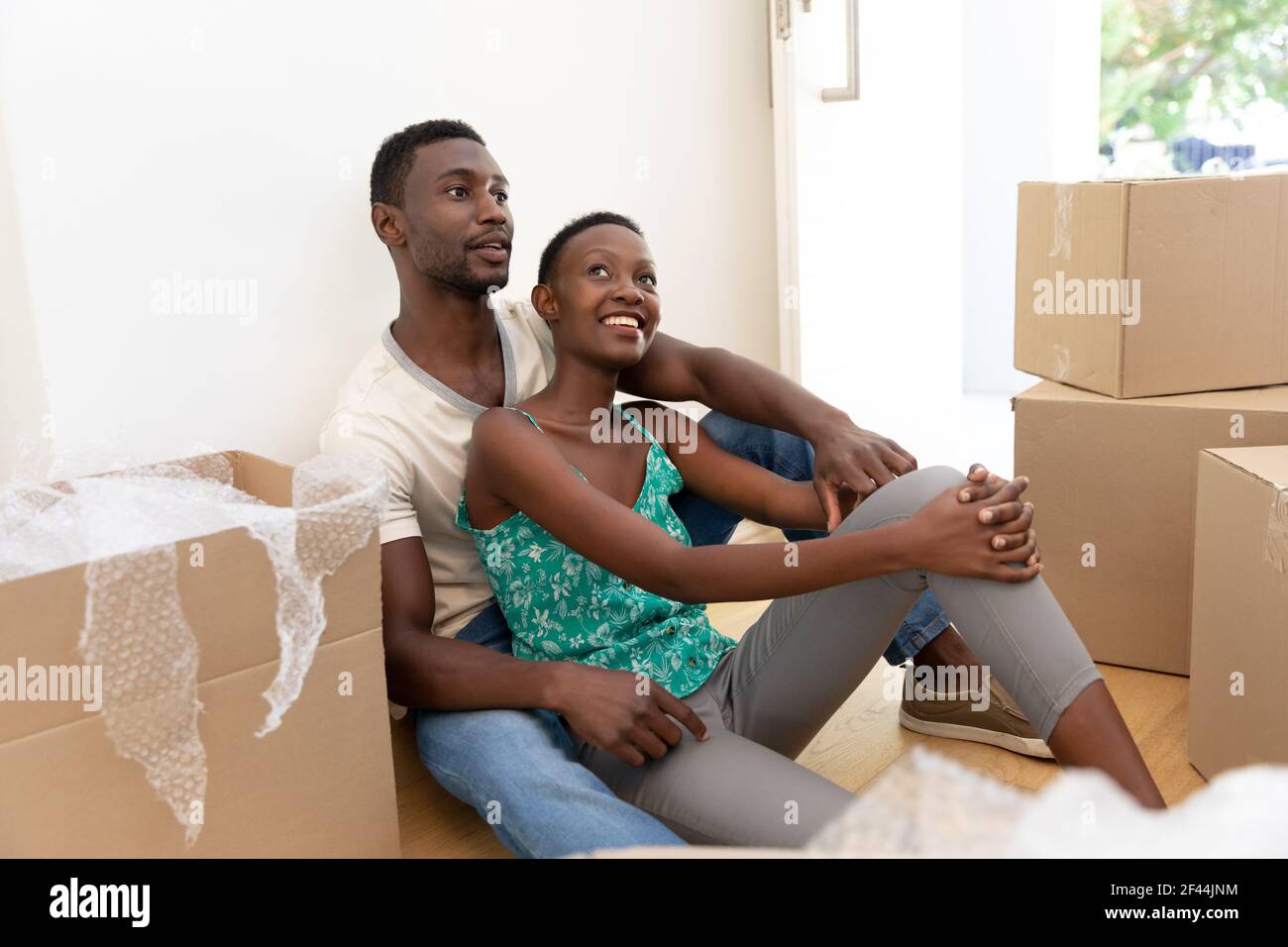 afroamerikanisches Paar Umzug Haus Auspacken sitzen auf dem Boden und Umarmen Stockfoto