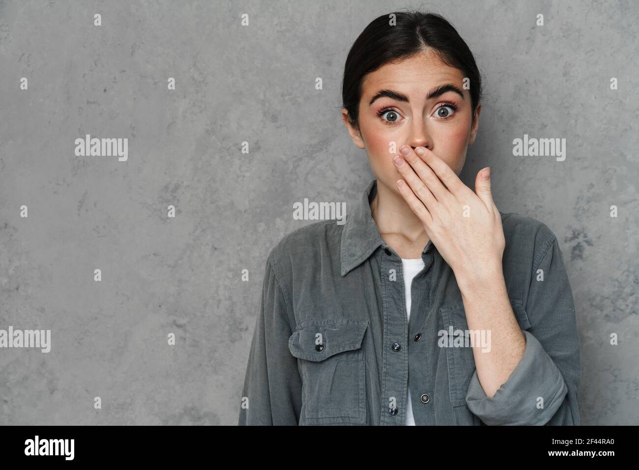 Schockiert schöne junge Frau schreiend über isolierten Hintergrund, hält die Hände über den Mund Stockfoto