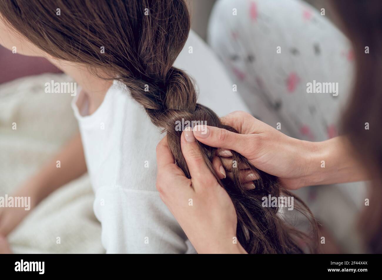 Weibliche Hände flechten lange dunkle Haare in Zopf Stockfoto