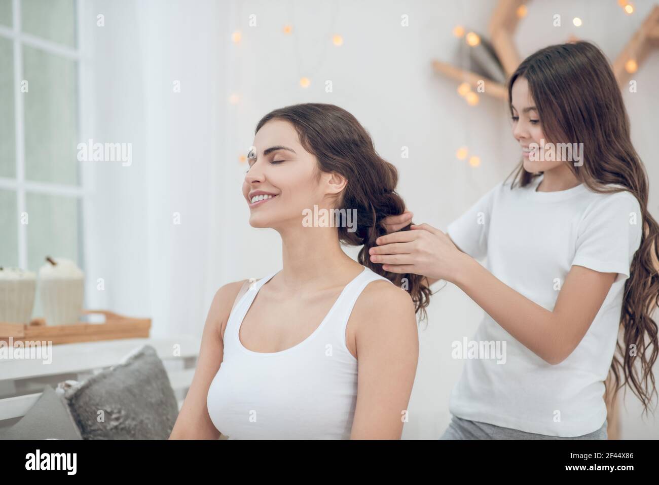 Tochter tun ihr Haar für glücklich Mutter Stockfoto