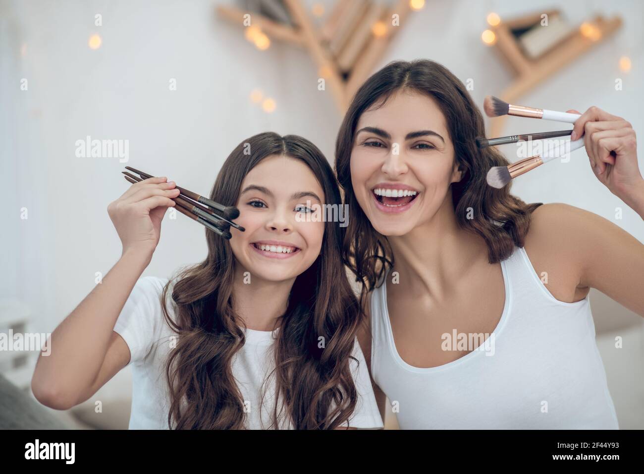 Enthusiastische Mutter und Tochter zeigen Make-up Pinsel Stockfoto