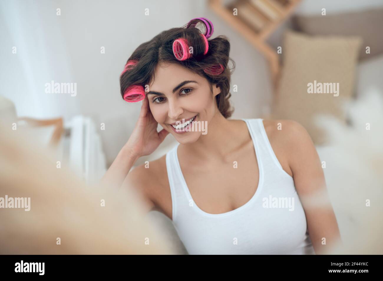 Schöne junge lächelnde Frau im Haar Lockenwickler Stockfoto