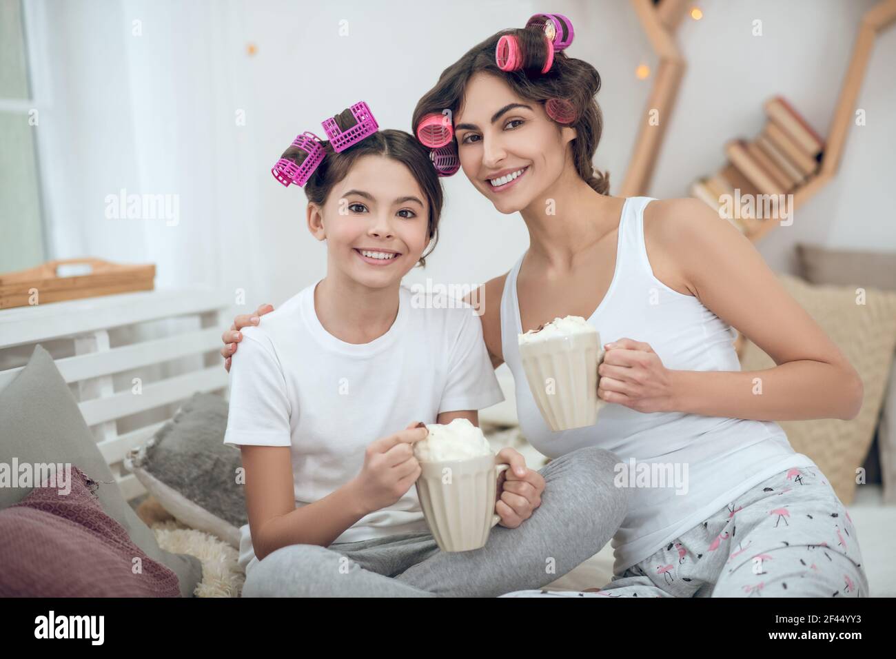 Mutter umarmt Tochter sitzen mit Kaffee zu Hause Stockfoto
