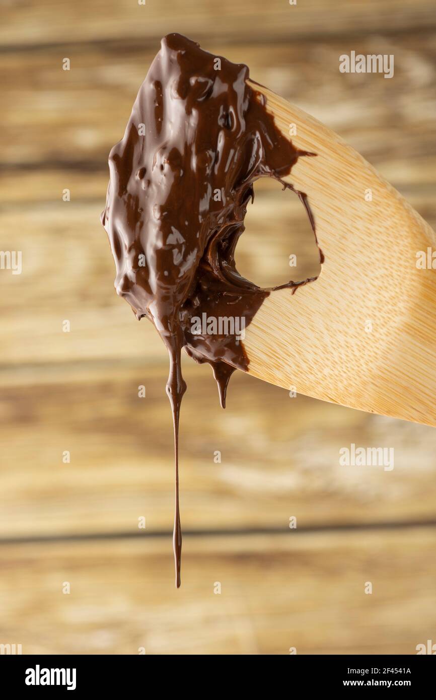 Geschmolzene Schokolade tropfend aus einem Holzlöffel. Stockfoto