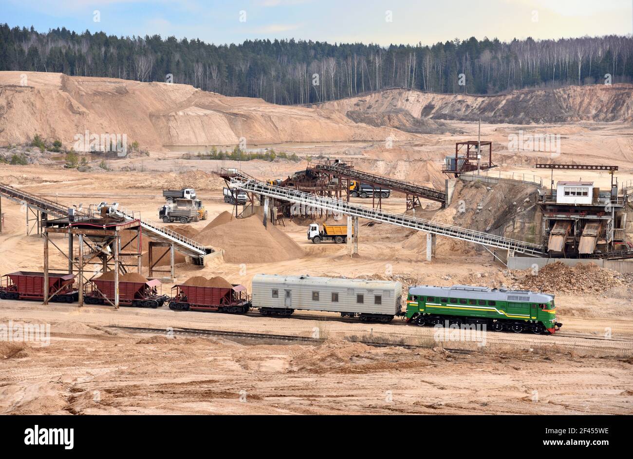 Verladung von Sand in Güterwagen eines Zuges im Steinbruch. Sandanlage im Tagebau. Zerkleinerung Fabrik, Maschinen und Anlagen zum Zerkleinern, Grinsen Stockfoto