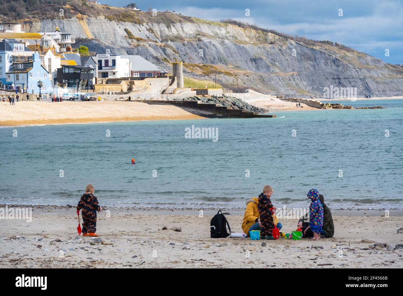 Lyme Regis, Dorset, Großbritannien. März 2021, 19th. UK Wetter: Eine gemischte Tüte von Sonnenschein und Wolke zusammen mit einer kühlen Brise im Badeort Lyme Regis. Eine Familie genoss es, den Strand für sich zu haben, da die erfrischende Meeresbrise die Leute fernhielt. Ungeklärte Bedingungen werden über das Wochenende prognostiziert Kredit: Celia McMahon/Alamy Live News Stockfoto