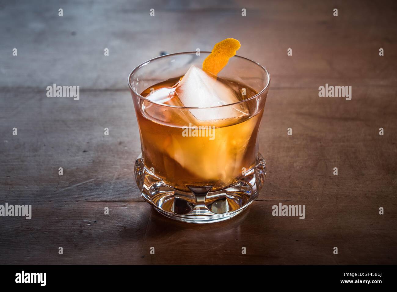 Altmodischer Cocktail mit Whiskey auf einem Holztisch mit Orange Twist in einem eleganten Retro Kristallglas Tumbler Stockfoto