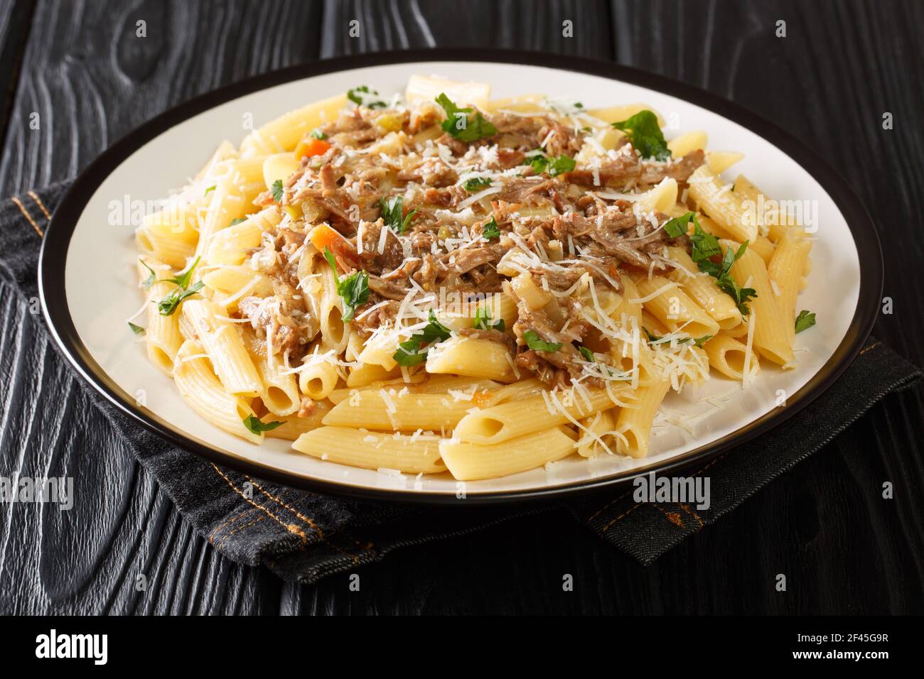 Penne Pasta alla Genovese Sauce mit Rindfleisch, Wein und Gemüse Nahaufnahme auf einem Teller auf dem Tisch. Horizontal Stockfoto