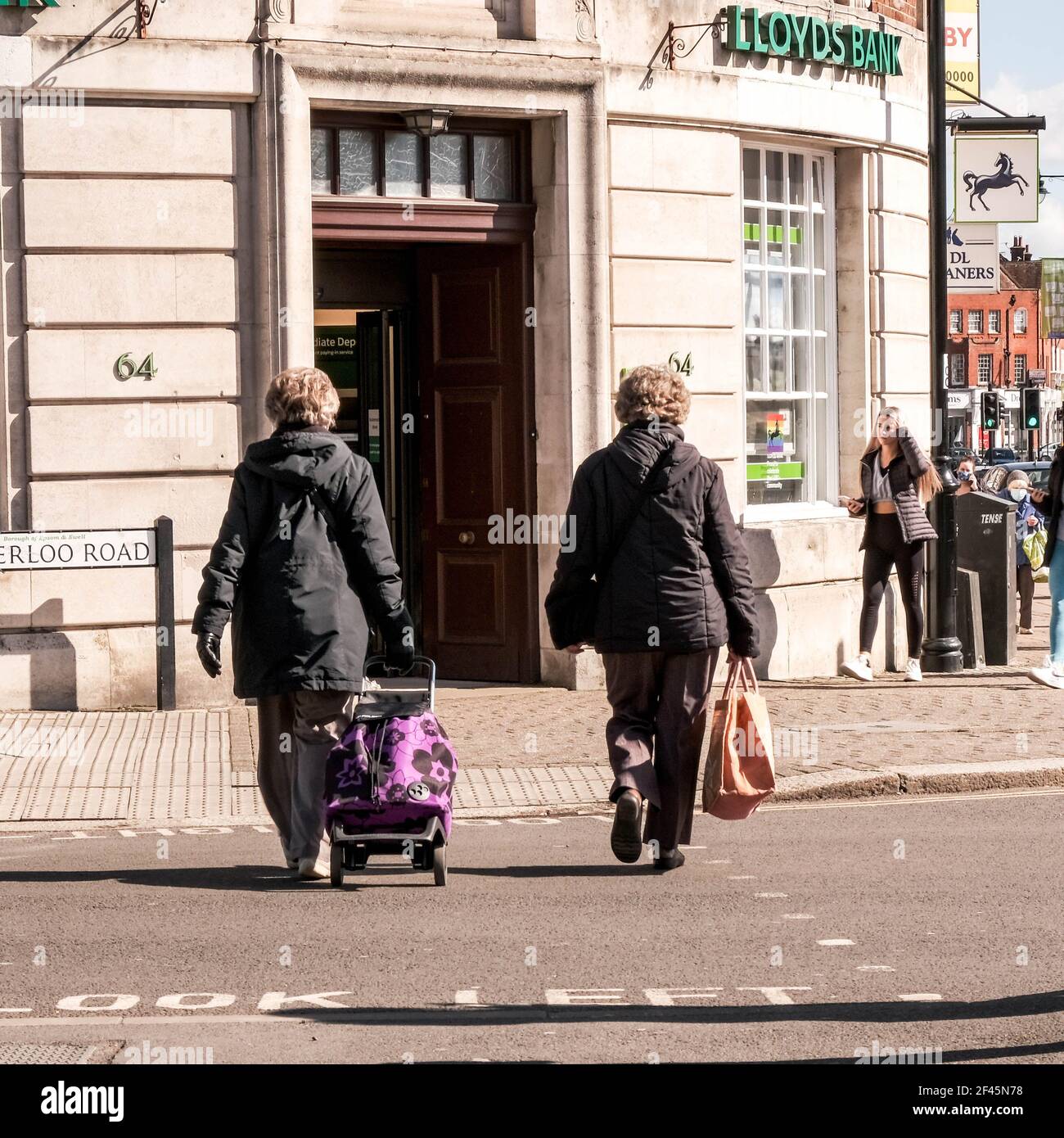 London, Großbritannien, März 19 2021, zwei Shopper-Frauen überqueren die Straße vor EINER Filiale der High Street Lloyds Bank Stockfoto