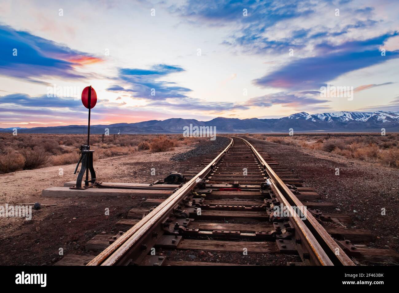 Die Eisenbahn spornt und schaltet in der Hochwüste im Nordwesten Nevadas früh morgens das Licht des Sonnenaufgangs ein. Burlington Northern Santa Fe Tracks. Stockfoto