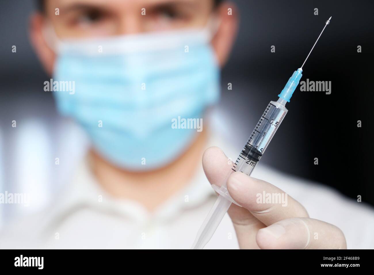 Spritze in Arzt Hand, Mann in medizinische Maske und Schutzhandschuhe Vorbereitung auf die Injektion. Konzept der Impfung während der Covid-19-Pandemie Stockfoto