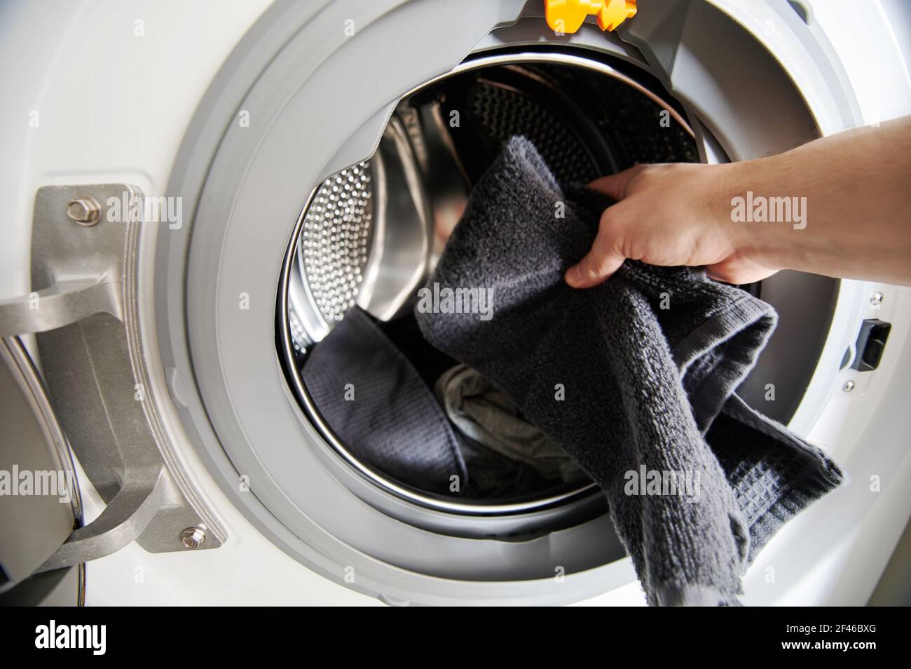 Legen Sie schmutziges Tuch von Hand in die Nahaufnahme der Waschmaschine Stockfoto