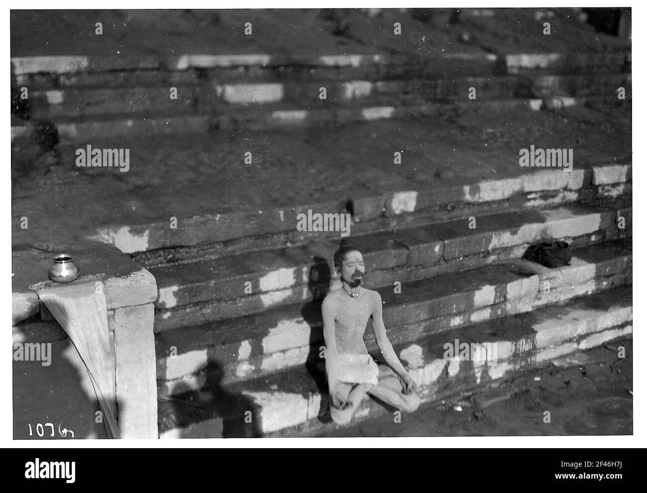 Varanasi (Benares), Indien. Heiliger Bartender, der nur mit Leih-Handtuch trägt, sitzt meditierend auf den Stufen eines Pilgerortes, wahrscheinlich auf dem ganges Stockfoto