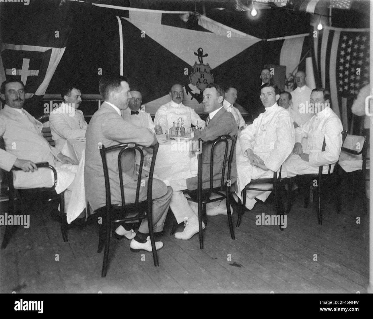 Kreuzfahrten der Hamburg-Amerika-Linie, um 1911/1913. Männer-Gruppe an gemeinsamen Lebensmitteln an Deck wäre auf einem Tiefsee-Passagierdampfer Cruises der Hamburg America Line, um 1911/1913. Männer-Gruppe bei gemeinsamen Essen auf Deck während eines Abends auf der Farm an Bord (?) Auf einem Hochsee-Passagierdampfer Stockfoto
