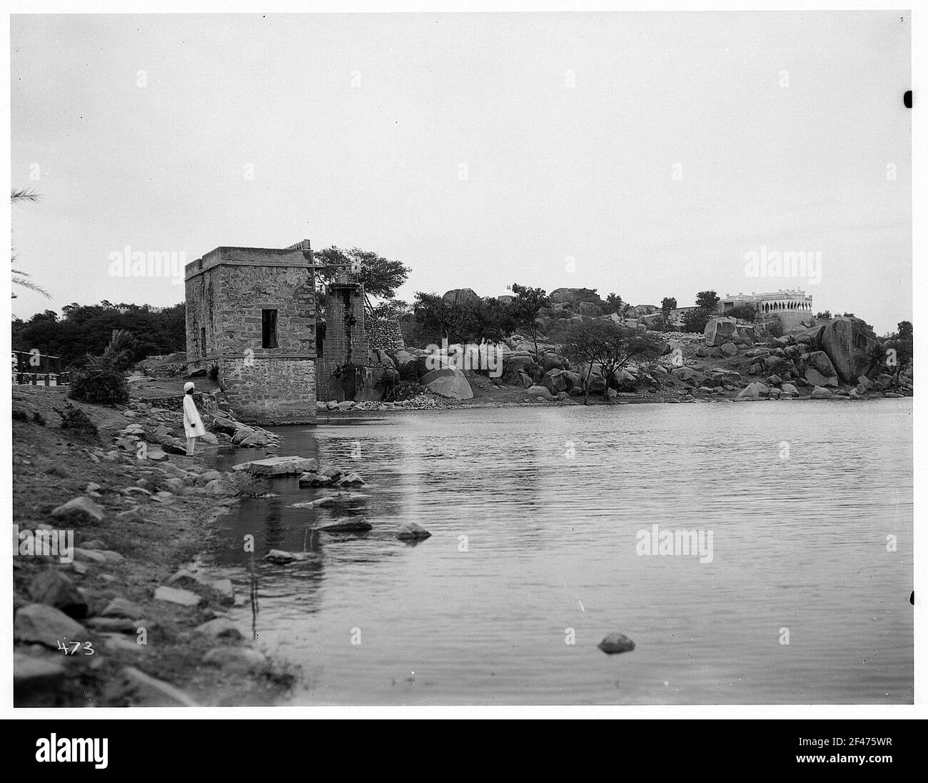 Rangonn, Burma. Lokal in traditioneller Kleidung mit Turban, auf einem steinigen Ufer stehend Stockfoto