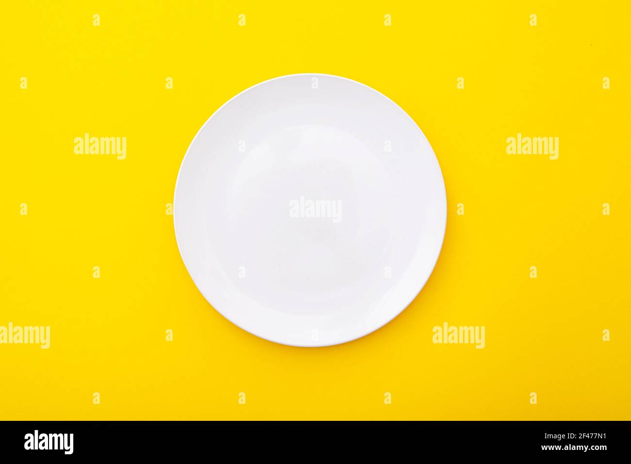 Weiße Keramikplatte auf gelber Oberfläche, Küchentisch, Layout, Draufsicht, Platz für Text Stockfoto
