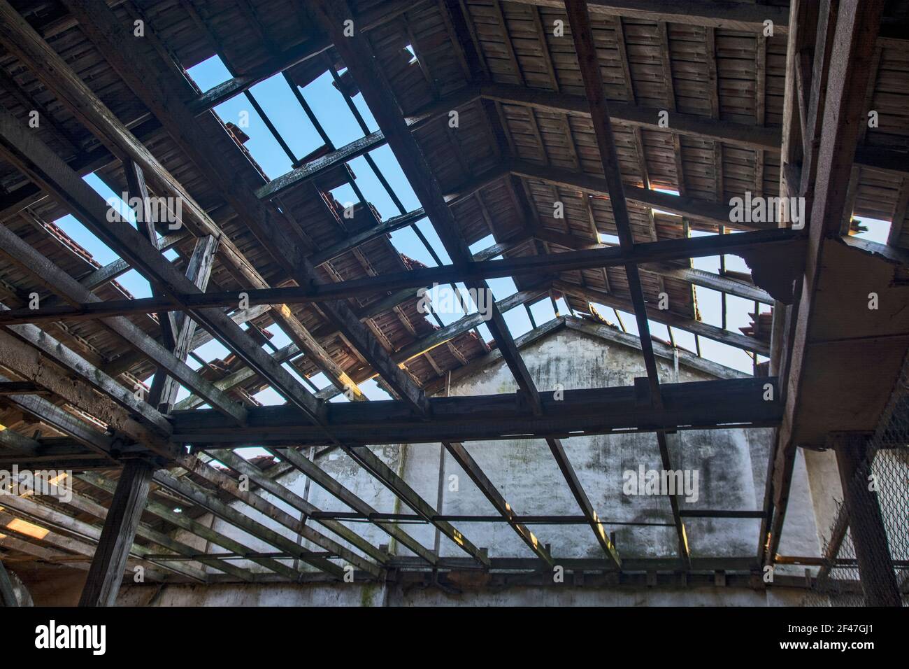 Ein altes zerstörtes Lagerhaus, das fast abgerissen wurde. Der Himmel kann durch das Dach gesehen werden. Das gesamte Gebäude ist anfällig für Abriss. Stockfoto