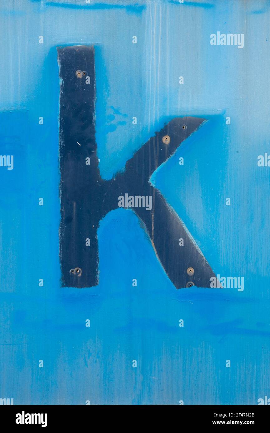 Die Spuren des verschwundenen Buchstabens k auf der ausgewaschenen blauen Oberfläche Stockfoto