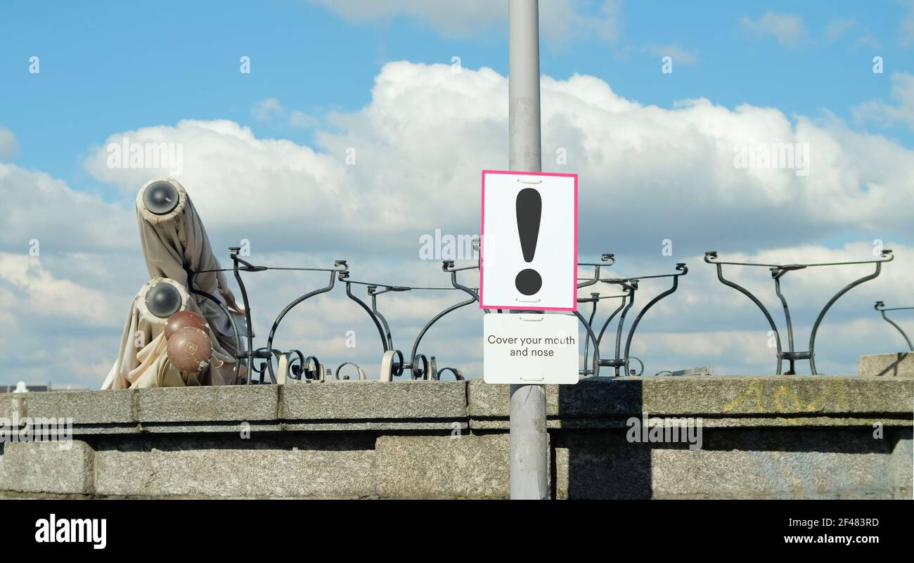 Gastronomie-Sperre, geschlossenes Restaurant und Warnschild. Gestapelte Tische und gefaltete Sonnenblenden im Freien, symbolisches Bild Stockfoto