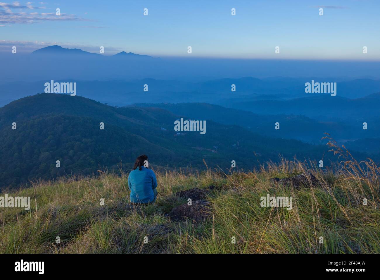 Eine Dame, die die herrliche Aussicht von einem Hügel in Wayanad am frühen Morgen genießt (Bild aufgenommen in Wayanad, Kerala) Stockfoto