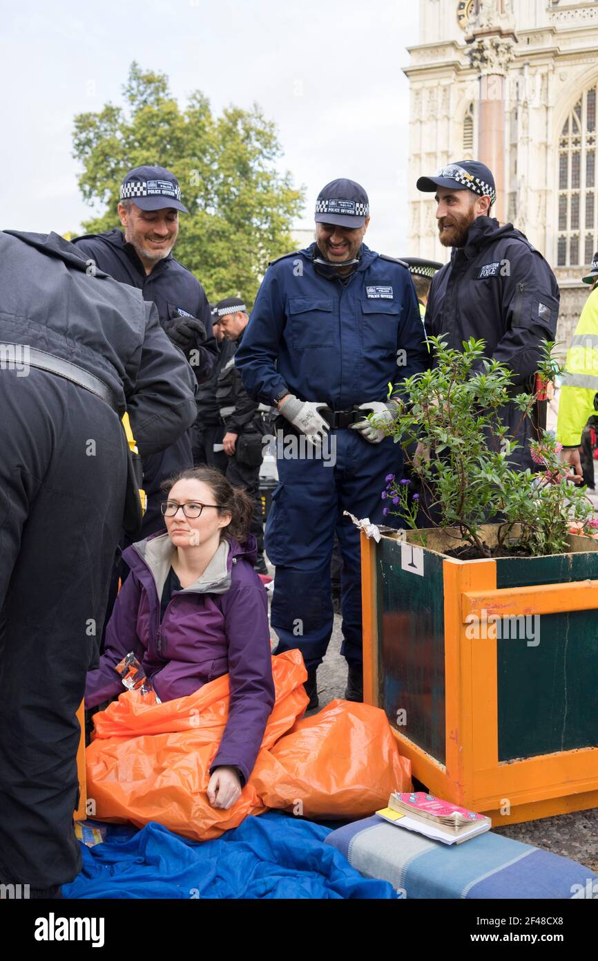 Polizeibeamte lächeln, als sie Beton durchsahen, indem sie die Protestierenden der Ausrottungsaufstand in der Hand hielten. London, England Stockfoto