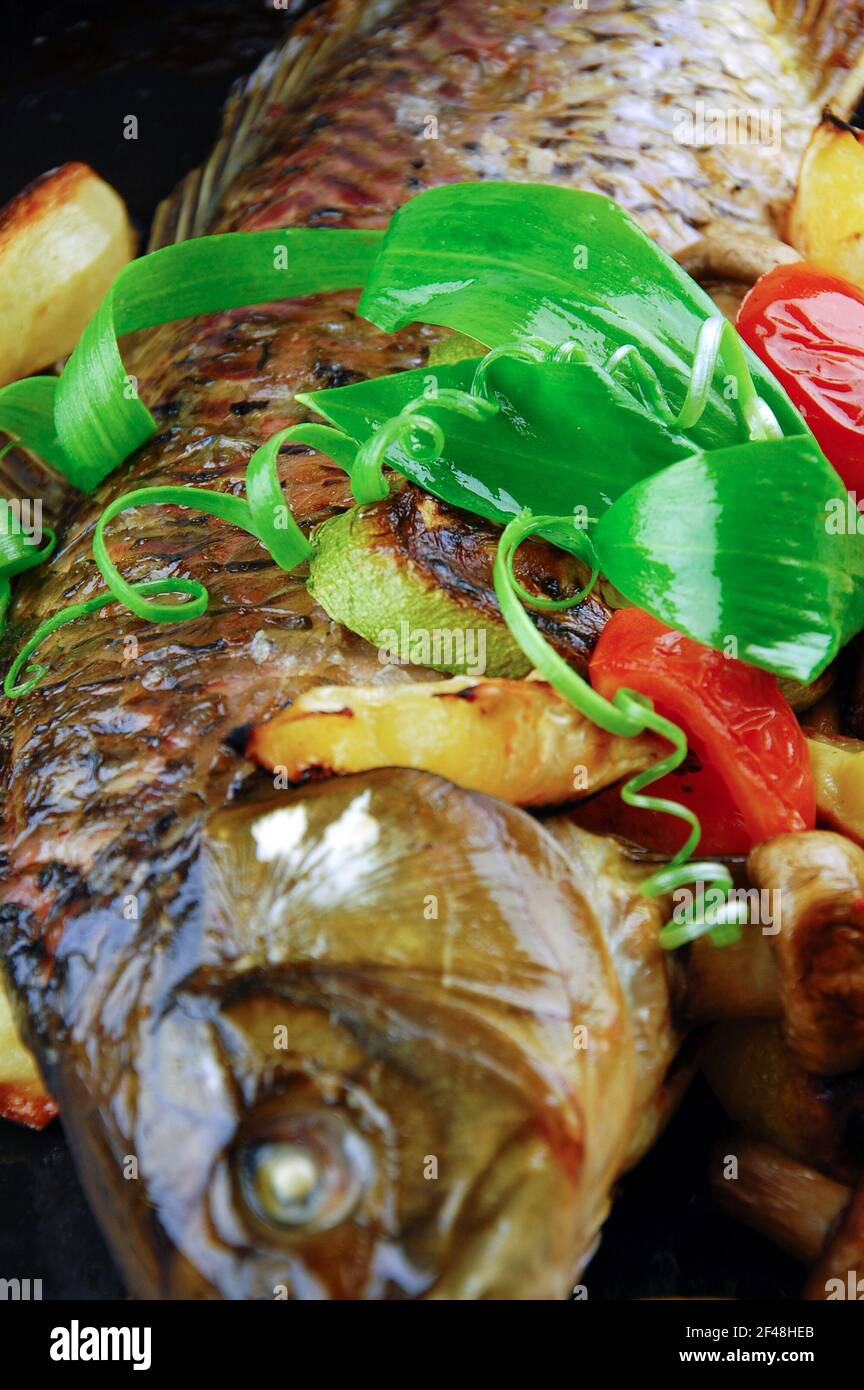 Gebackener Fisch mit Gemüse, Pilzen und Zitrone. Stockfoto