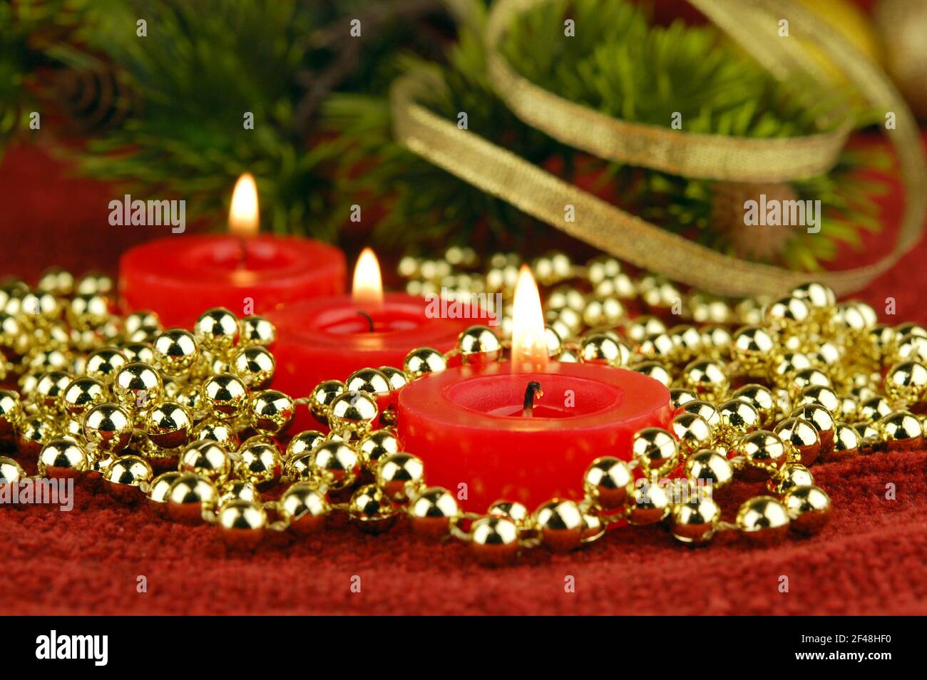 Drei Kerzen mit weihnachtlichen Dekorationen als abstrakter festlicher Hintergrund. Konzentrieren Sie sich auf einen ersten Docht. Neujahrs- oder Weihnachtskarte. Stockfoto