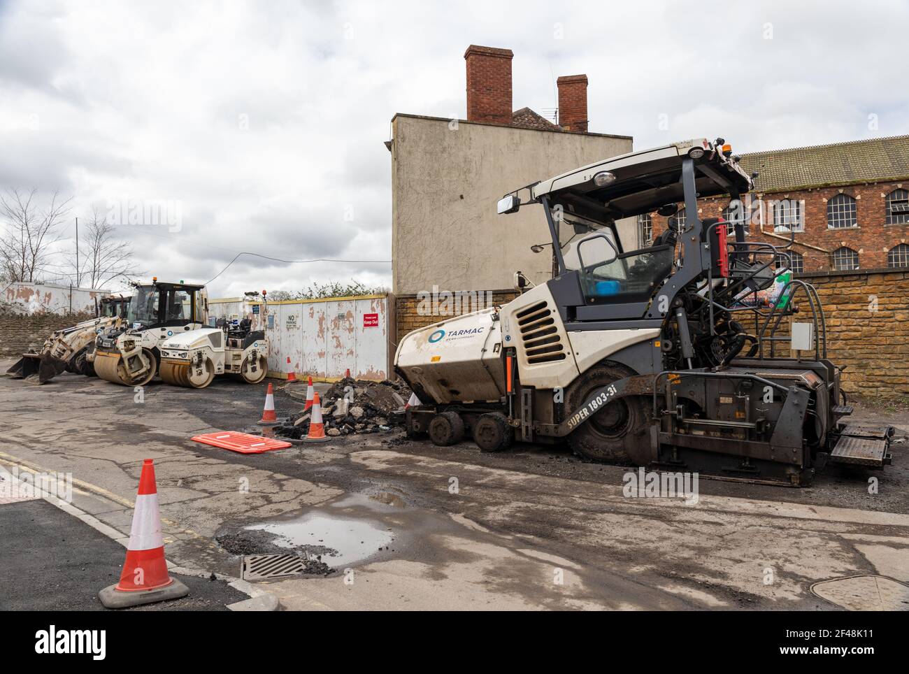 Asphaltierte Fahrzeuge, einschließlich Vogele Straßenfertiger, parkten neben dem alten Fabrikgelände der Bogenschützen, bereit für die Autobahnwartung in Trowbridge, Wiltshire, Großbritannien Stockfoto