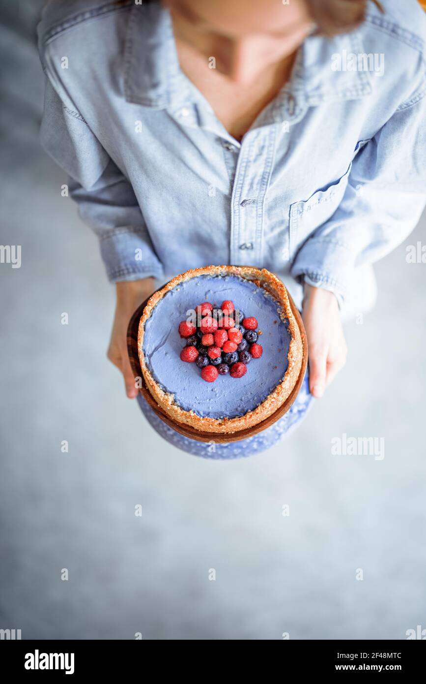 Frau trägt Käsekuchen mit Himbeere und Heidelbeere verziert, Blick von oben Stockfoto