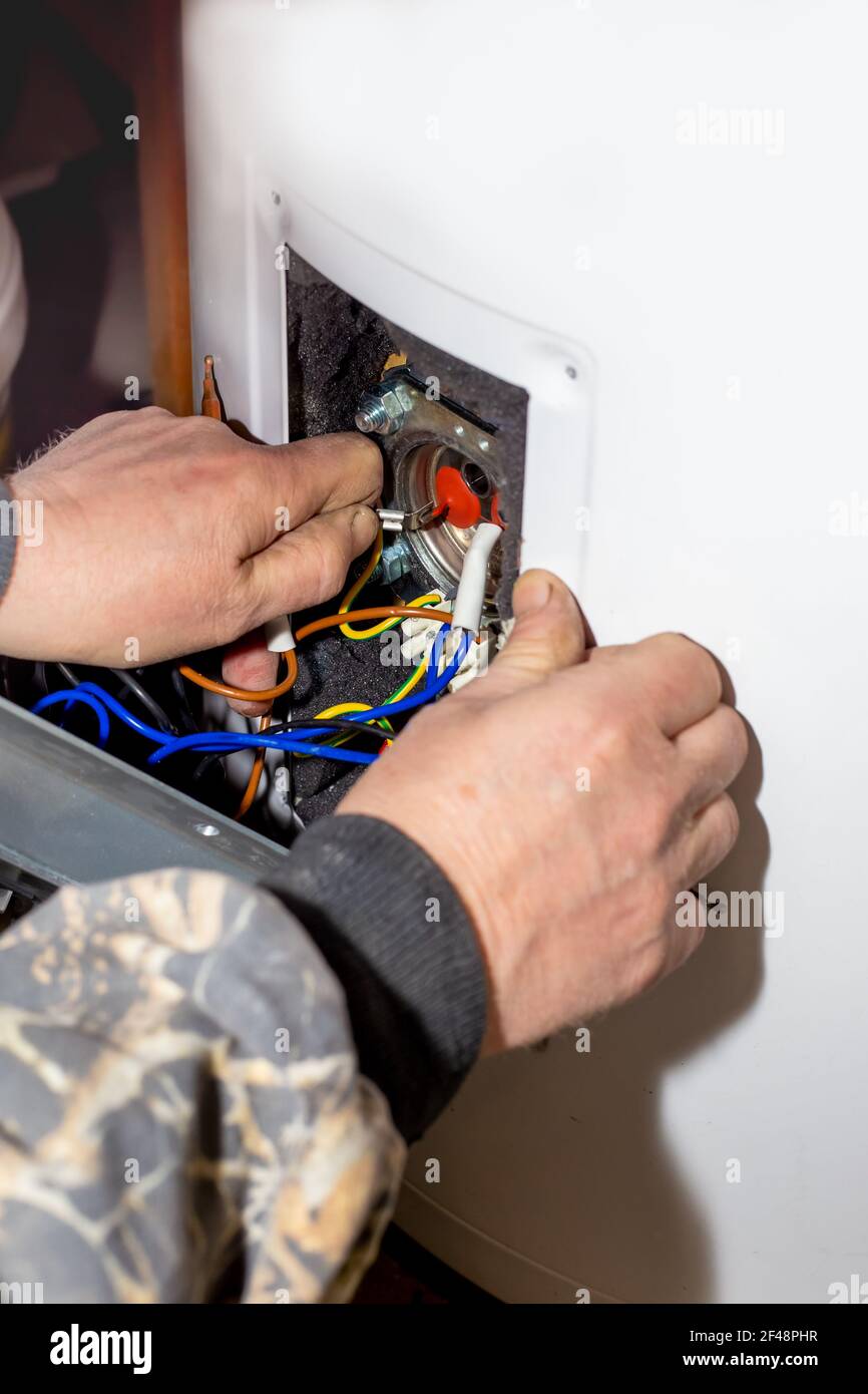 Der Vorarbeiter demontierte den Elektrokessel für Reparatur und Wartung. Heizungssteuerrelais. Stockfoto