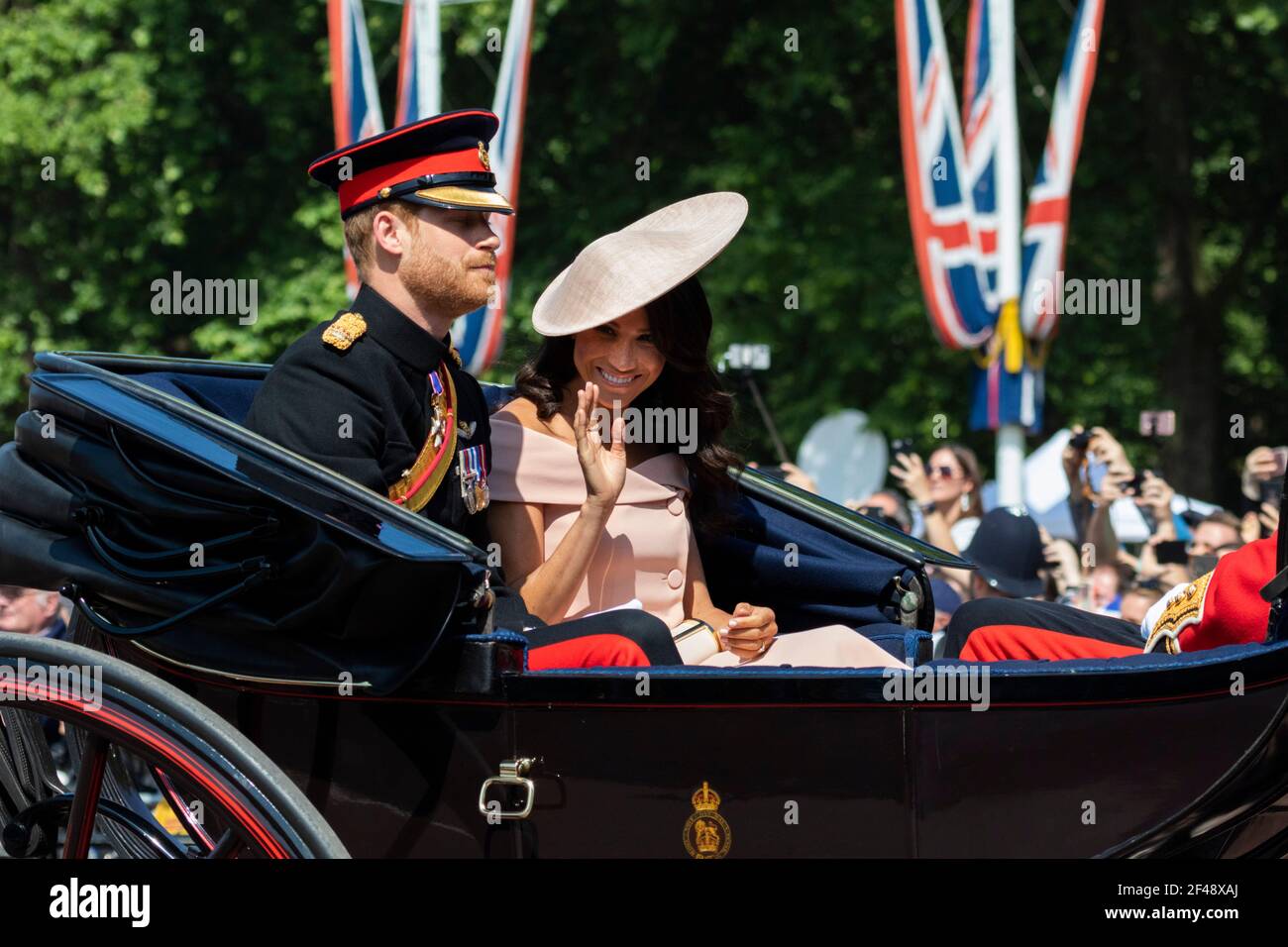 Meghan Markle Herzogin von Sussex winkt der Menge zu, während Reiten in einer Kutsche mit Prinz Harry in Trooping of Die Farbe Stockfoto