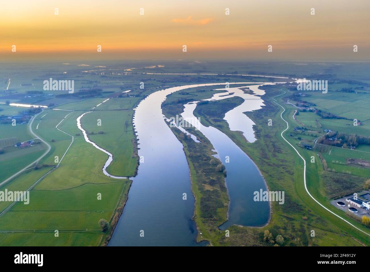 Luftaufnahme des riesigen Tieflandflusses IJssel durch Sonnenuntergangslandschaft. Zwolle, Overijssel Provinz, Niederlande. Drohnenszene in der Natur Europas. Stockfoto