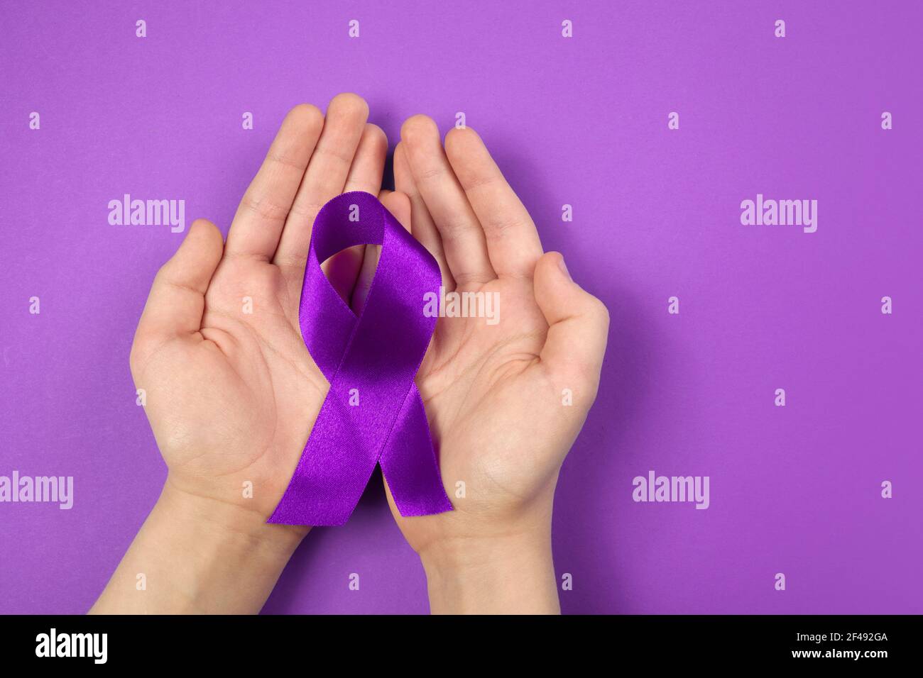 Violetter Tag. Welttag der Epilepsie. Hände mit violettem Band auf violettem Hintergrund Stockfoto