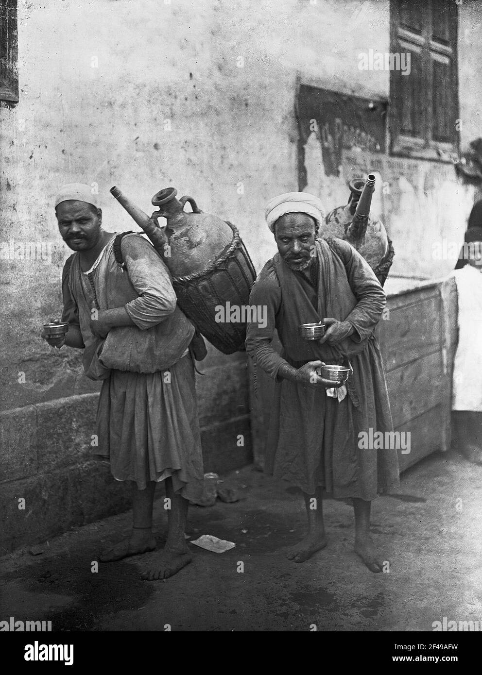 Kairo (? Ägypten). Wasser gewellt mit spürbaren Retention der Schulter und Metallschalen in der Hand auf einer Straße Kairo (Ägypten). Wasserverkäufer mit getönten Behältern über der Schulter und Metallschüsseln in der Hand auf einer Straße Stockfoto