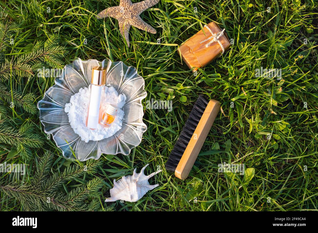 Natürliche, umweltfreundliche Reinigungswerkzeuge: Soda in Glasblumenschale in der Nähe von Bambusbürste, saubere hausgemachte Lösung und ein Fläschchen mit ätherischem Öl, Seife auf grün Stockfoto