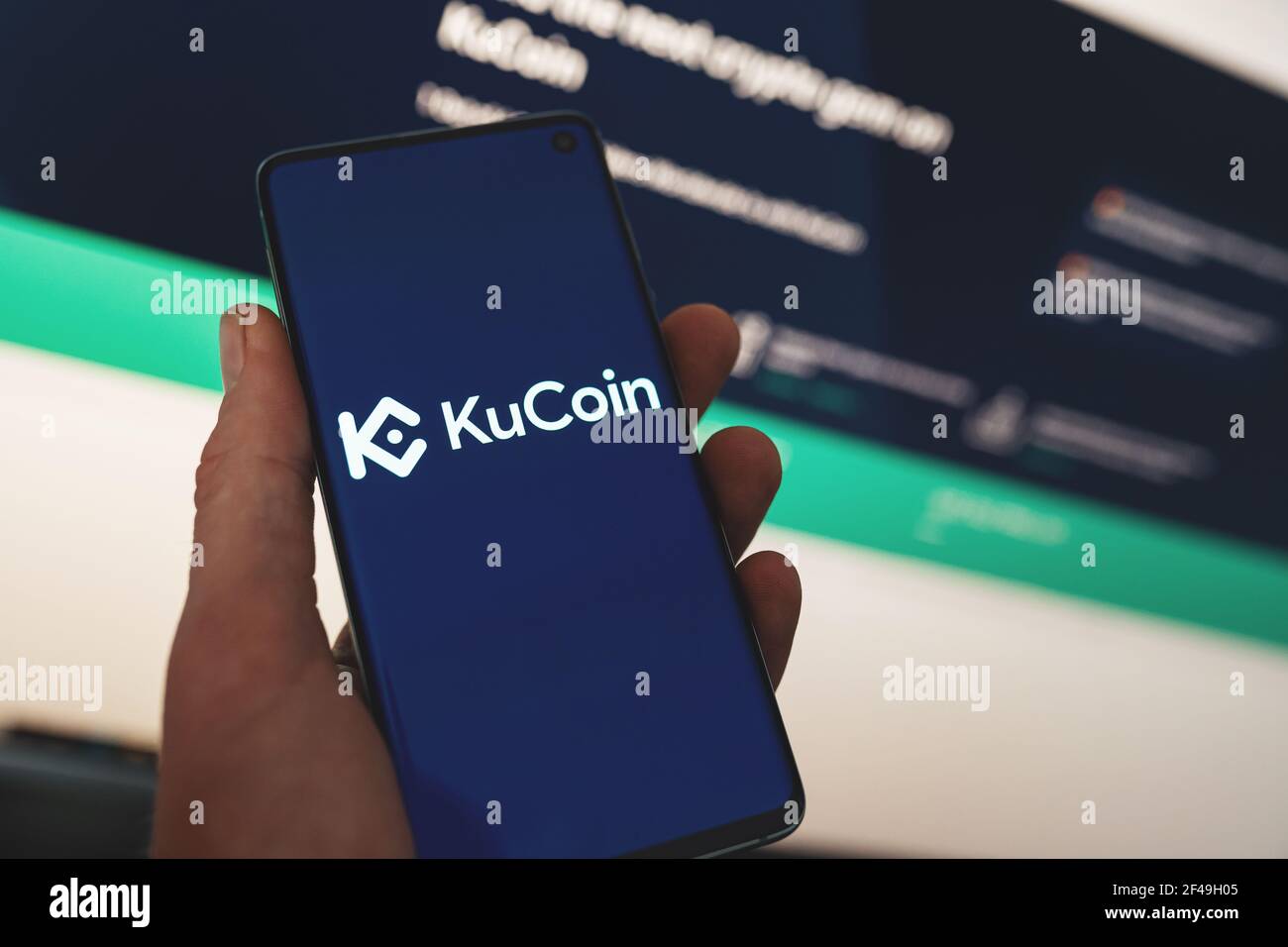 Mann hält ein Smartphone mit KuCoin App-Logo mit verschwommenem Website-Hintergrund. Kryptowährungsbörse, Handelsplattform Stockfoto