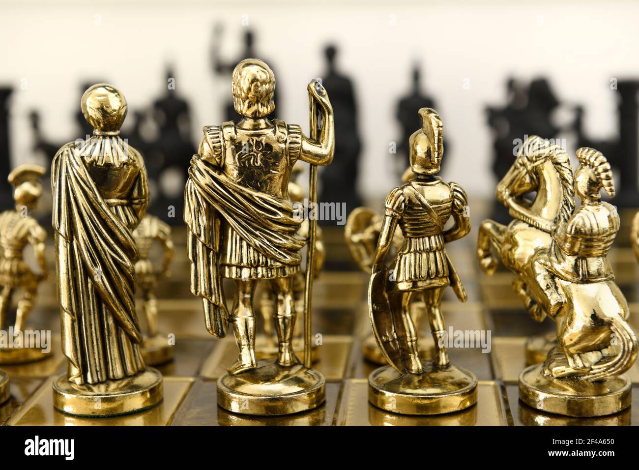 Rückseite der goldenen Königin König Centurion und Ritter Schach Stück Figuren auf Schachbrett mit Blick auf schwarz gegnerische Armee Stockfoto