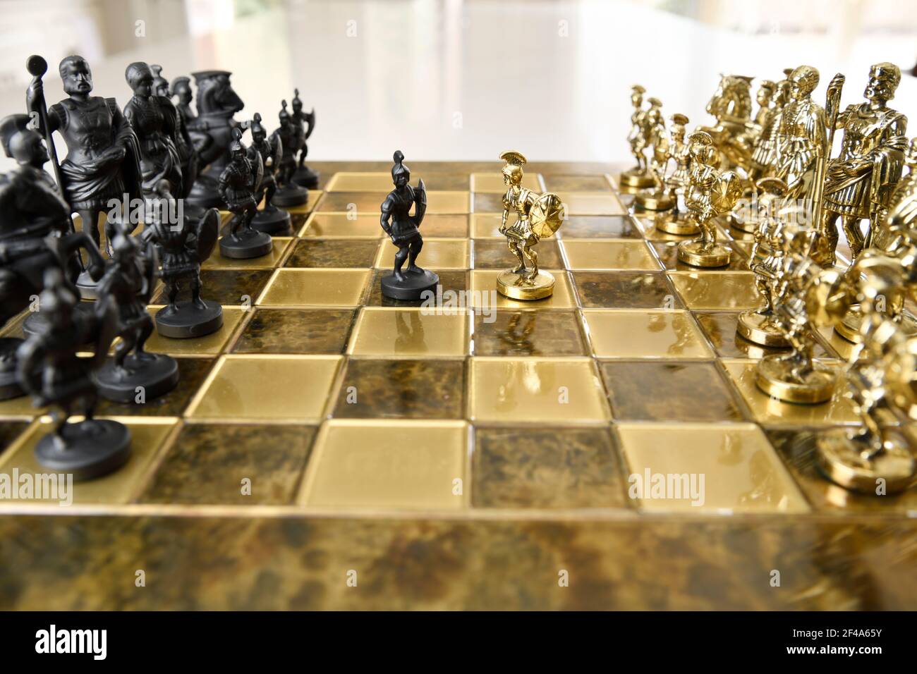 Schwarz und Gold Metall römischen Zenturion Bauer Schachfiguren aus Gegnerische Armeen auf Schachbrett bereit für den Kampf Stockfoto
