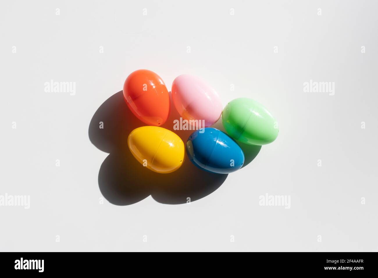 Draufsicht auf fünf bunte Kunststoff-Ostereier in der Sonne isoliert auf weißem Hintergrund. Stockfoto