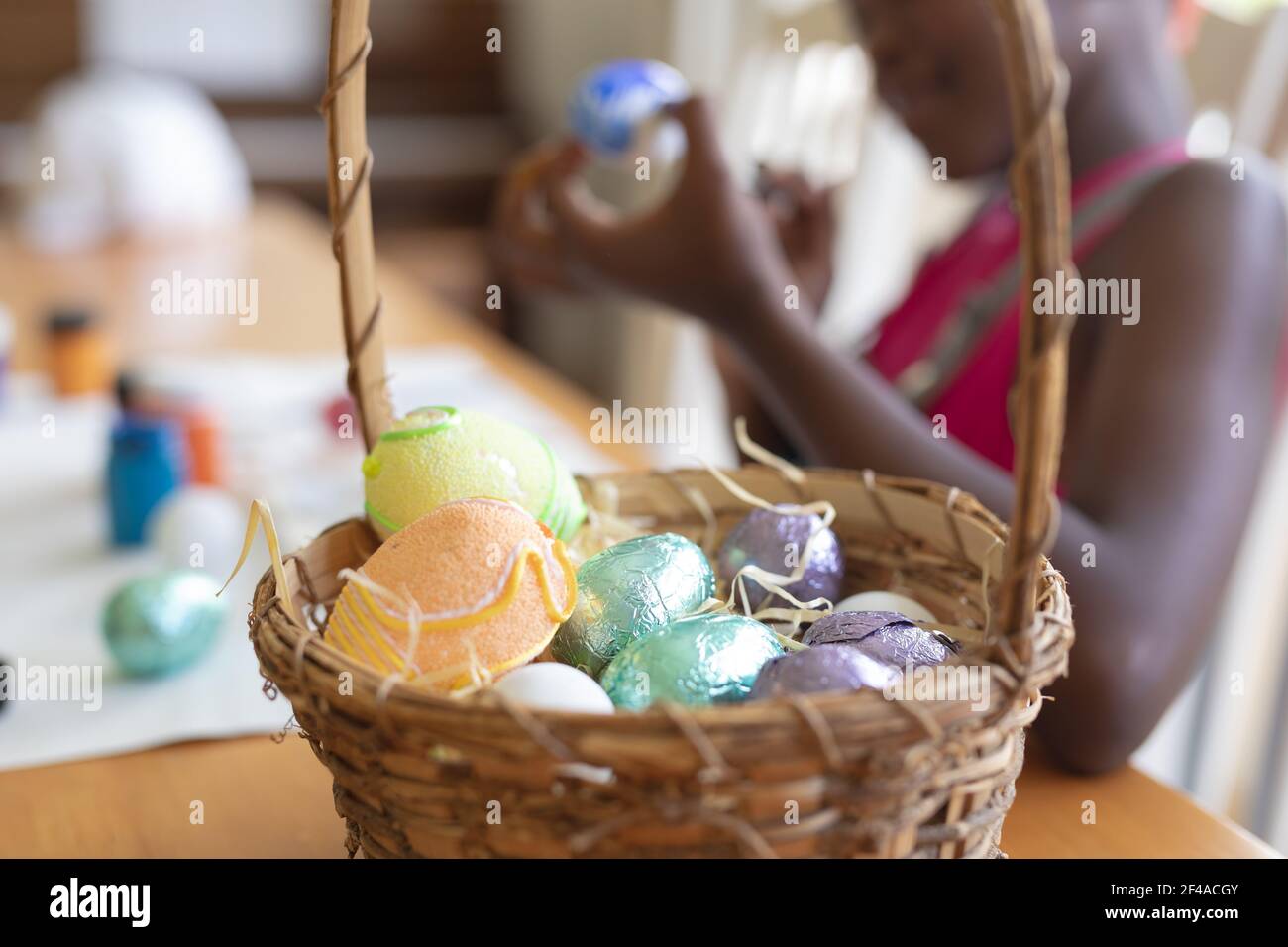 Korb mit bunten Eiern mit afroamerikanischen Mädchen malen in Der Hintergrund Stockfoto