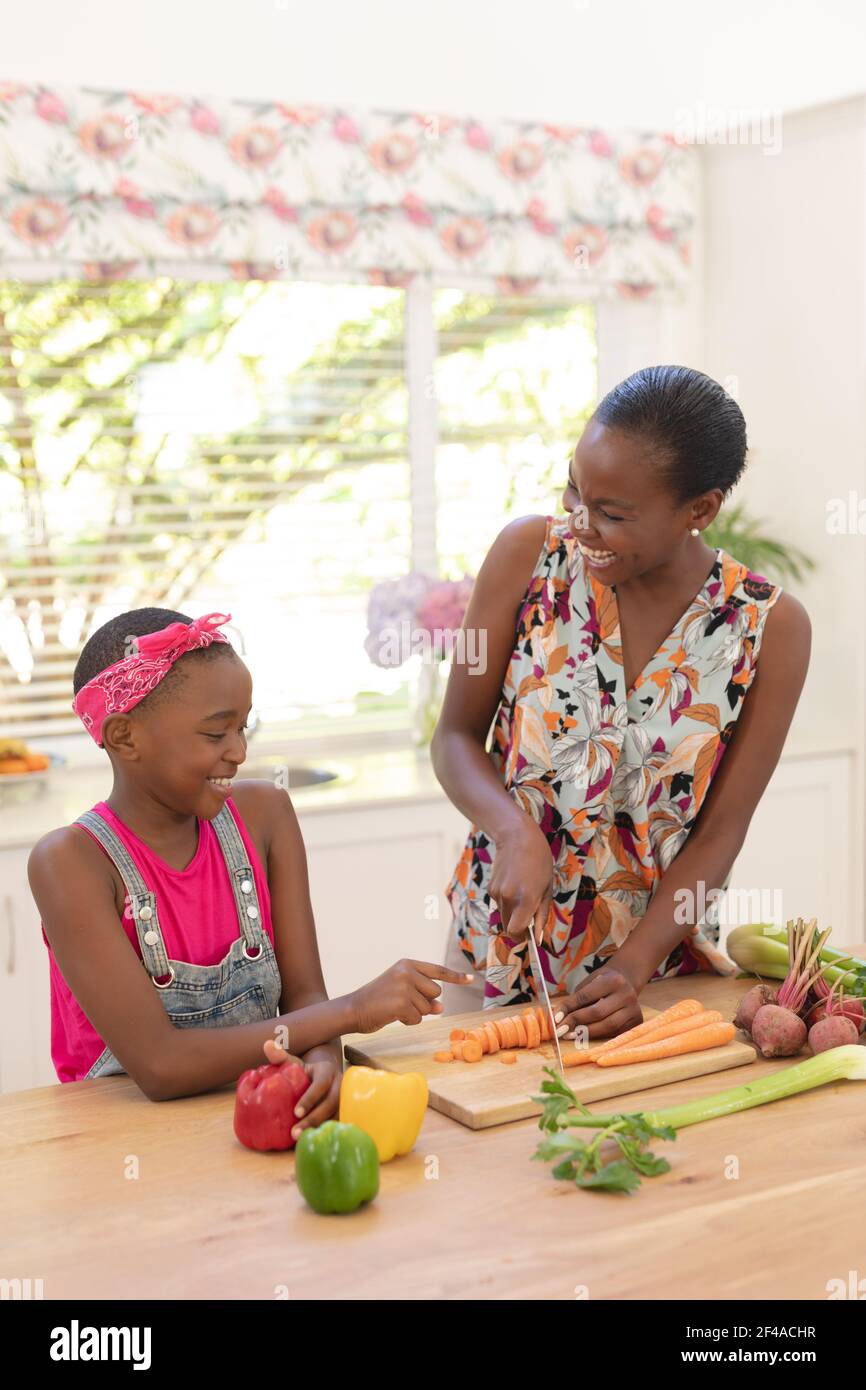 Lächelnde afroamerikanische Mutter lehrt Tochter Kochen in der Küche Stockfoto