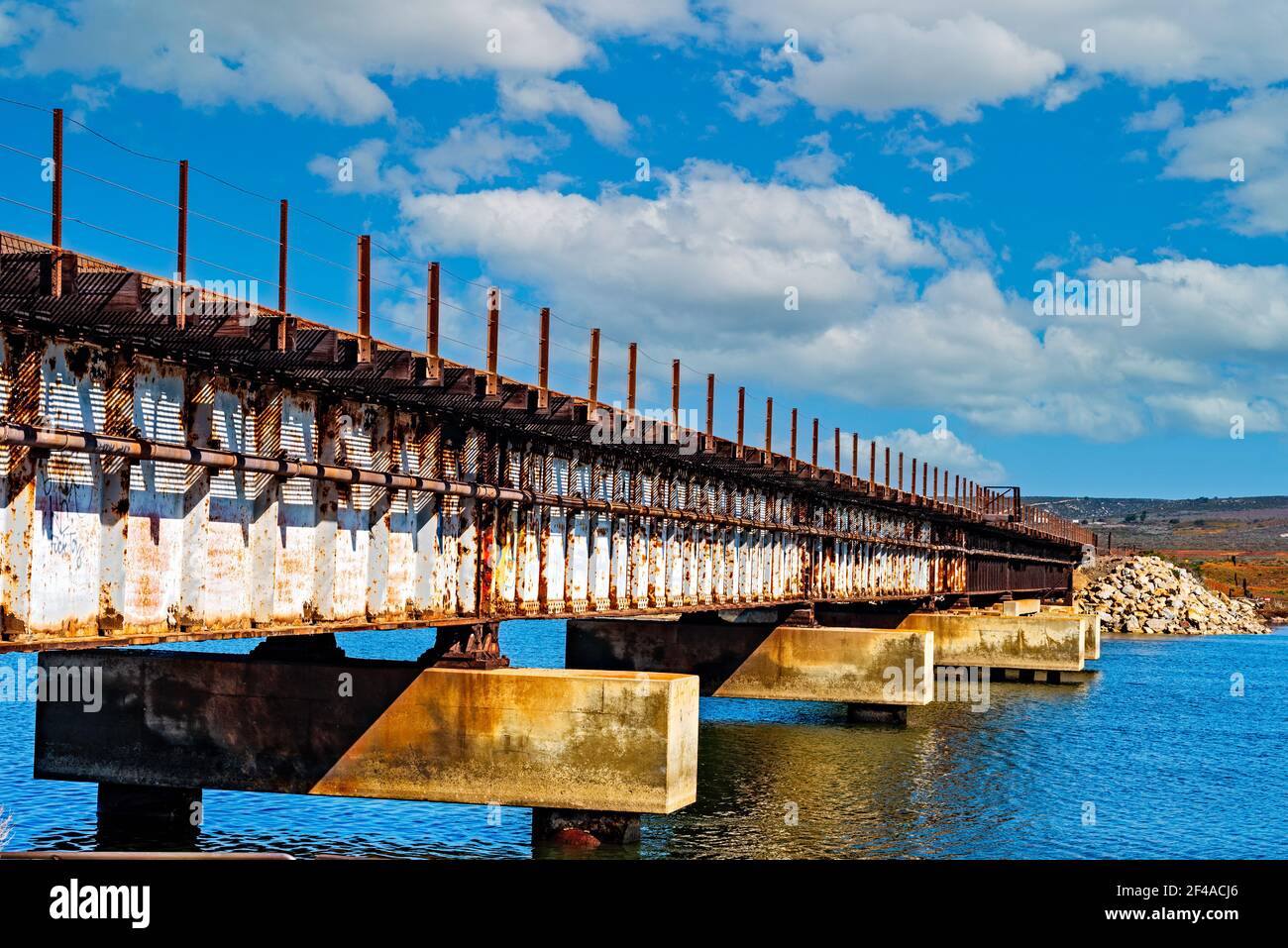 Alte Stahlzugbrücke über den Fluss unter blauem Himmel mit weißen Wolken. Stockfoto