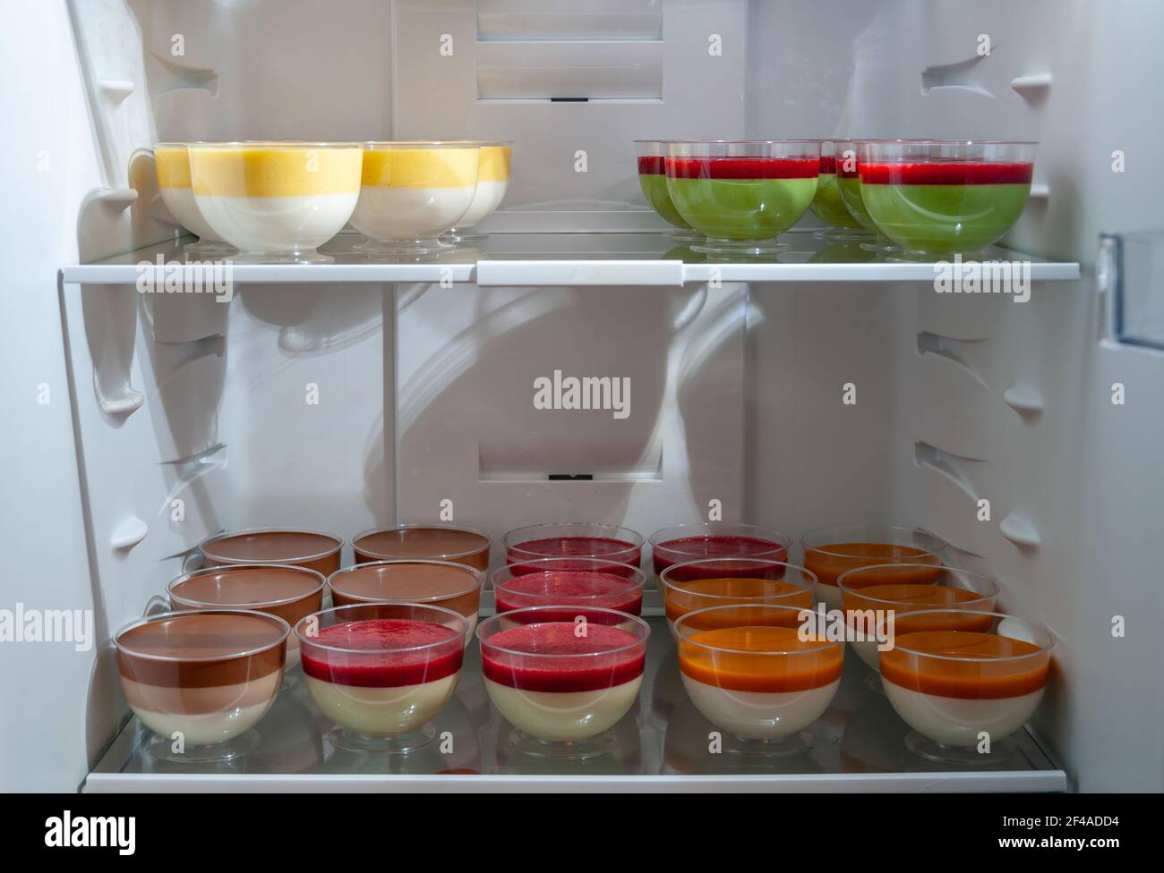 Vielfalt an süßen leckeren Desserts in Plastikgläsern im Kühlschrank, selektiver Fokus. Köstliche Panna Cotta mit Himbeeren. Stockfoto